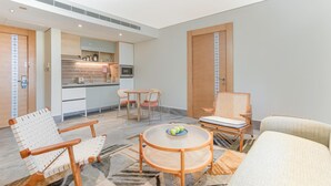 A modern living room with a round coffee table, two armchairs, a sofa, and a kitchen area with a dining table and chairs. - Ewaa Express Hotel-Al Shati (Jeddah)