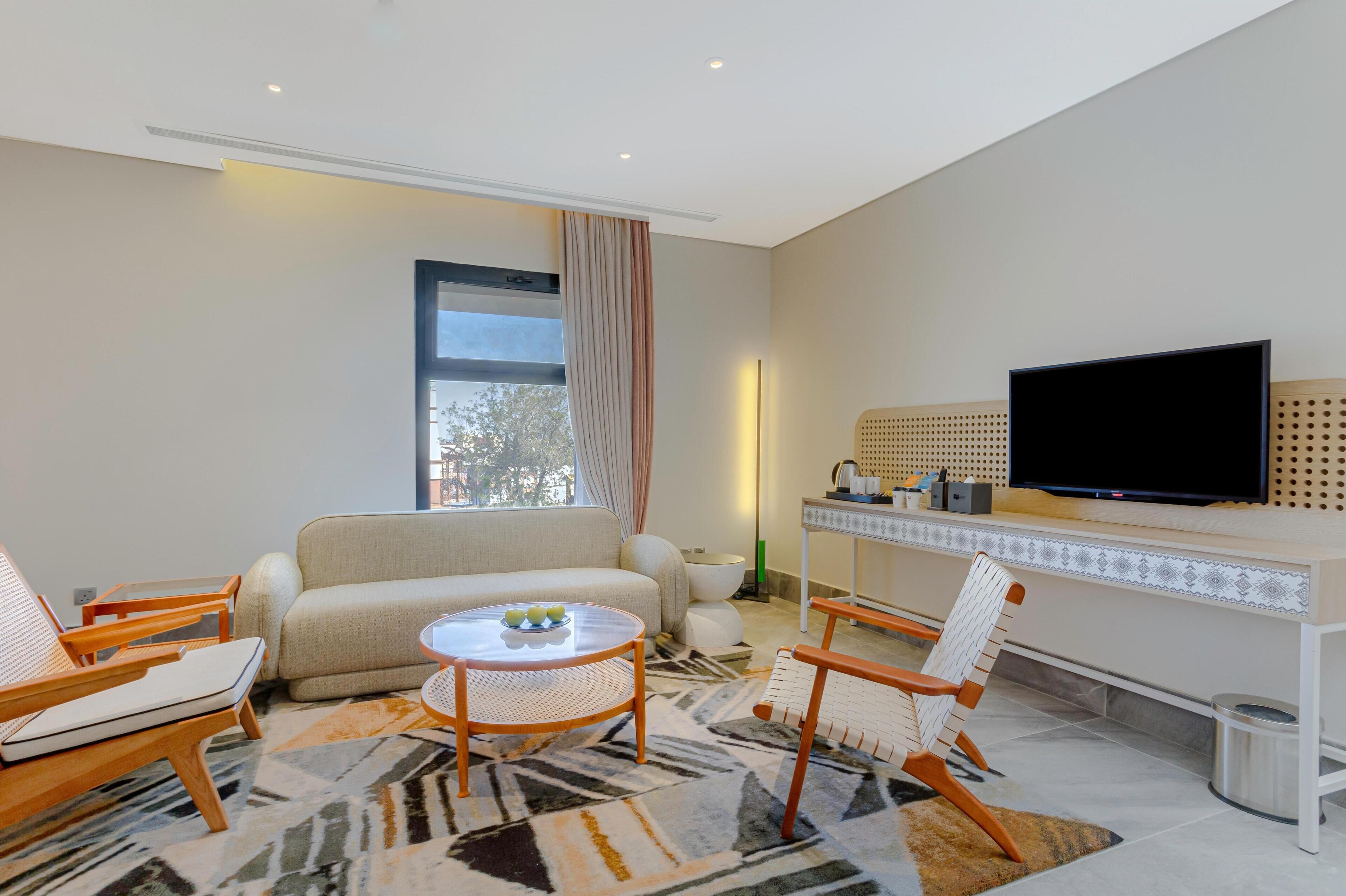 Uma sala de estar moderna com um sofá, duas poltronas, uma mesa de centro e uma televisão de tela plana fixada na parede.