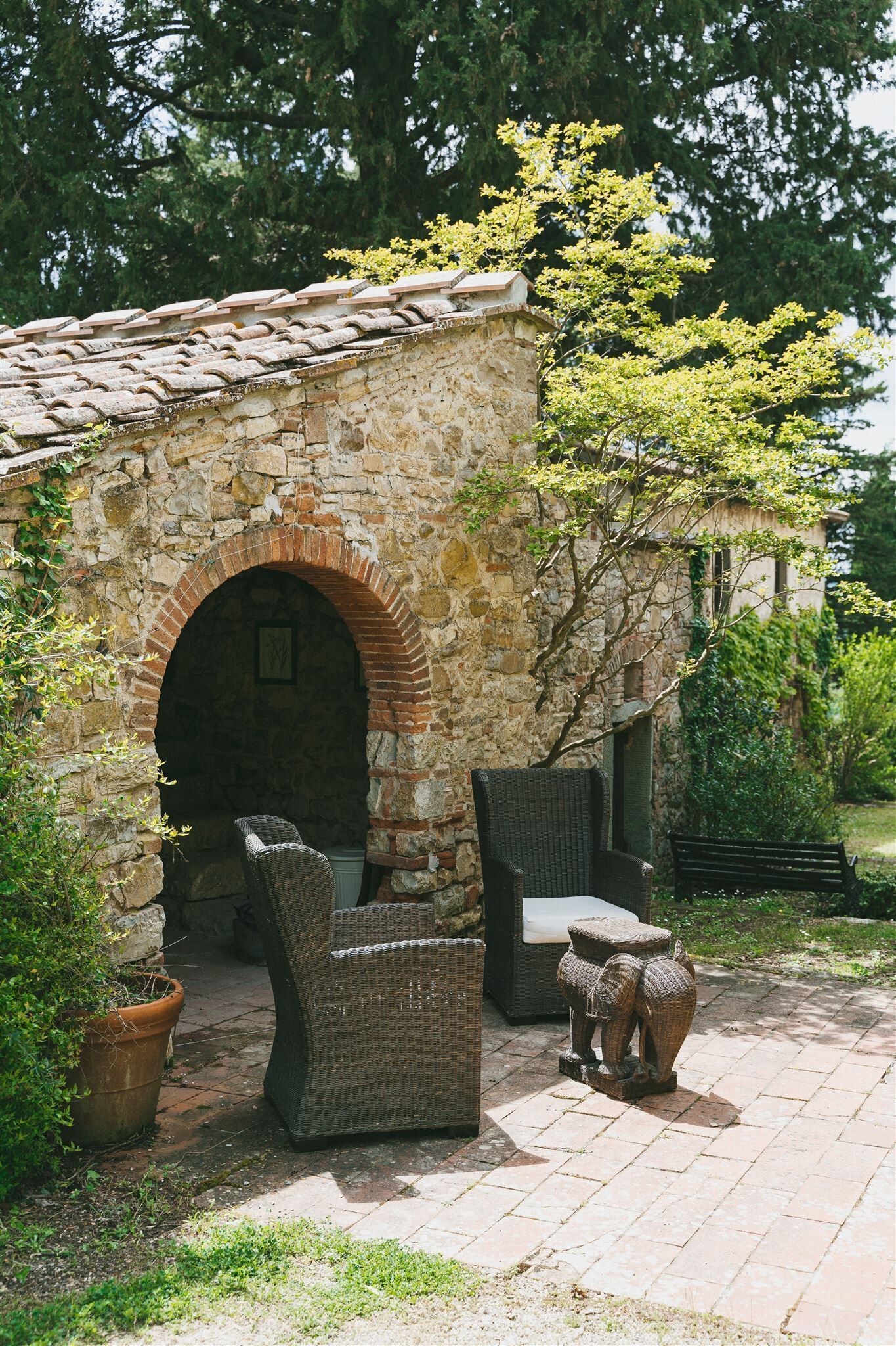 A stone building with an arched entrance, wicker furniture, and a decorative elephant figure.