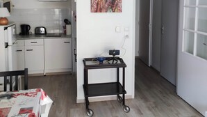 Una cocina moderna con armarios blancos, una lámpara colgante y una pequeña mesa con un teléfono inteligente.