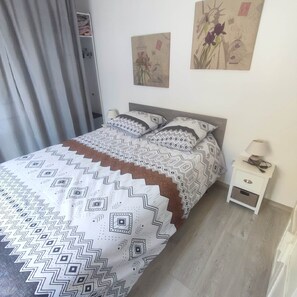 A bedroom with a bed, a nightstand, and two wall art pieces.