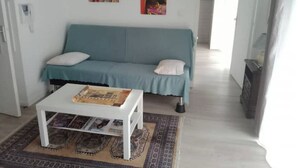 Una sala de estar con un sofá color turquesa, una mesa de centro blanca y una alfombra estampada.