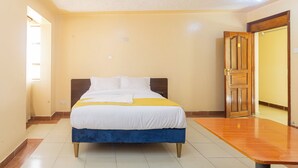 Une chambre d’hôtel avec un lit, une table en bois et une porte.