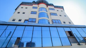 Un bâtiment moderne doté d’une façade en verre réfléchissant, de nombreuses fenêtres et d’une colonne centrale imposante.