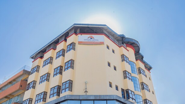 Un hôtel à plusieurs étages, avec une enseigne indiquant que des chambres sont disponibles.