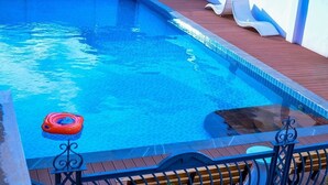 A swimming pool with a wooden deck and lounge chairs. - Canwin Hotel (Accra)