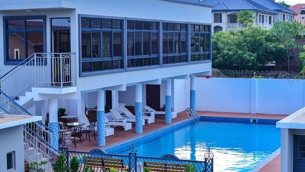A modern two-story house with a swimming pool, large windows, and a balcony. - Canwin Hotel (Accra)