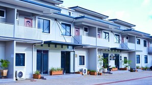 A modern multi-story hotel with balconies, air conditioning units, and potted plants. - Canwin Hotel (Accra)