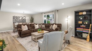 A living room with a brown sofa, striped armchairs, a coffee table, and a bookshelf. - Modern [3BR/2BA] Family Home in Commerce Township (Commerce Township)
