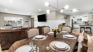 A modern dining area with a wooden table set for six, surrounded by cushioned seating. - Modern [3BR/2BA] Family Home in Commerce Township (Commerce Township)