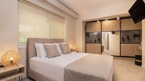 A modern bedroom with a large bed, bedside lamps, a wardrobe, and a TV mounted on the wall. - Fratelli Villa, with Heated Pool & Spa Whirlpool  (Zakynthos)