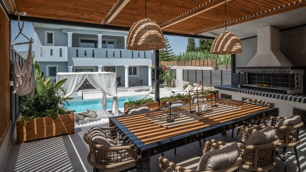 An outdoor dining area with a long table, wicker chairs, and hanging lights. - Fratelli Villa, with Heated Pool & Spa Whirlpool  (Zakynthos)