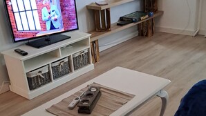 Una sala de estar con televisor, una mesa de centro y una estantería.