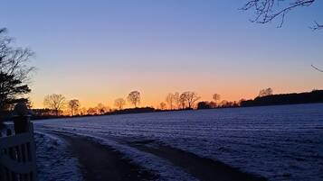 Un sentier enneigé qui mène à un plan d’eau, avec un coucher de soleil en arrière-plan.