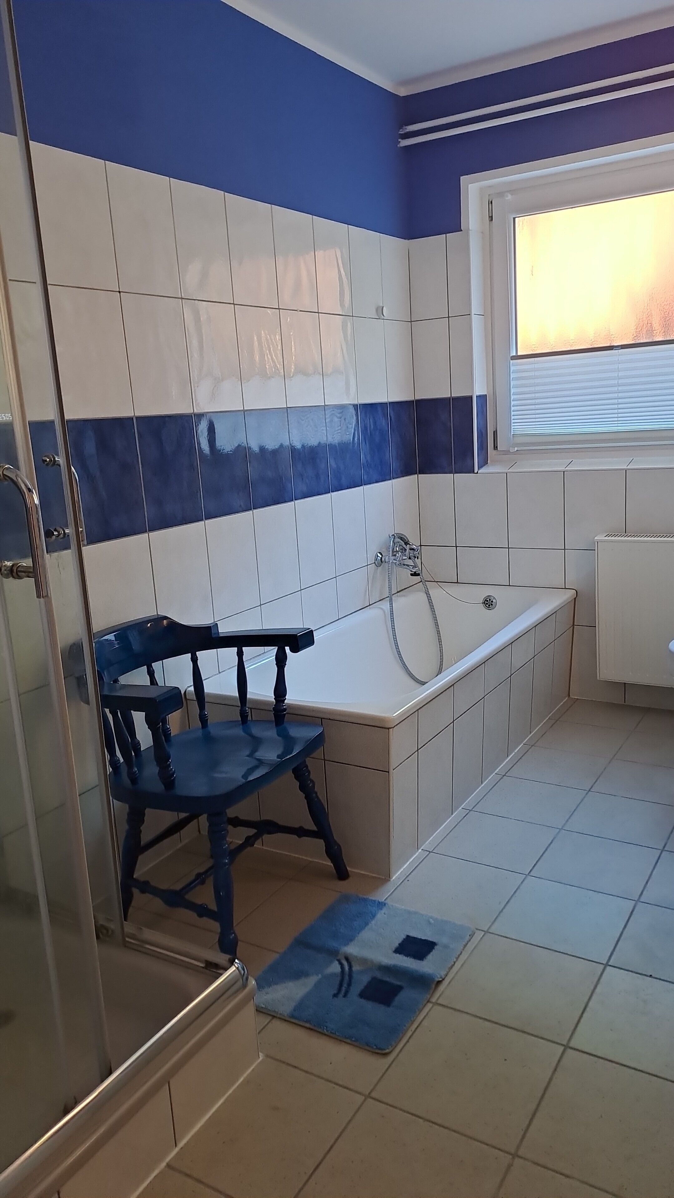 Een badkamer met een bad, douche en raam.