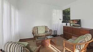 Una sala de estar con sofá, sillón y televisor sobre un mueble de madera.