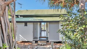 A small, single-story building with a green metal roof and a covered porch. - One bedroom cottage - Ideal couples retreat (Point Lookout)