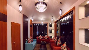 A modern living room with a chandelier, sofas, and a coffee table. - The Sky Imperial  Nakoda Green Valley  (Nathdwara)