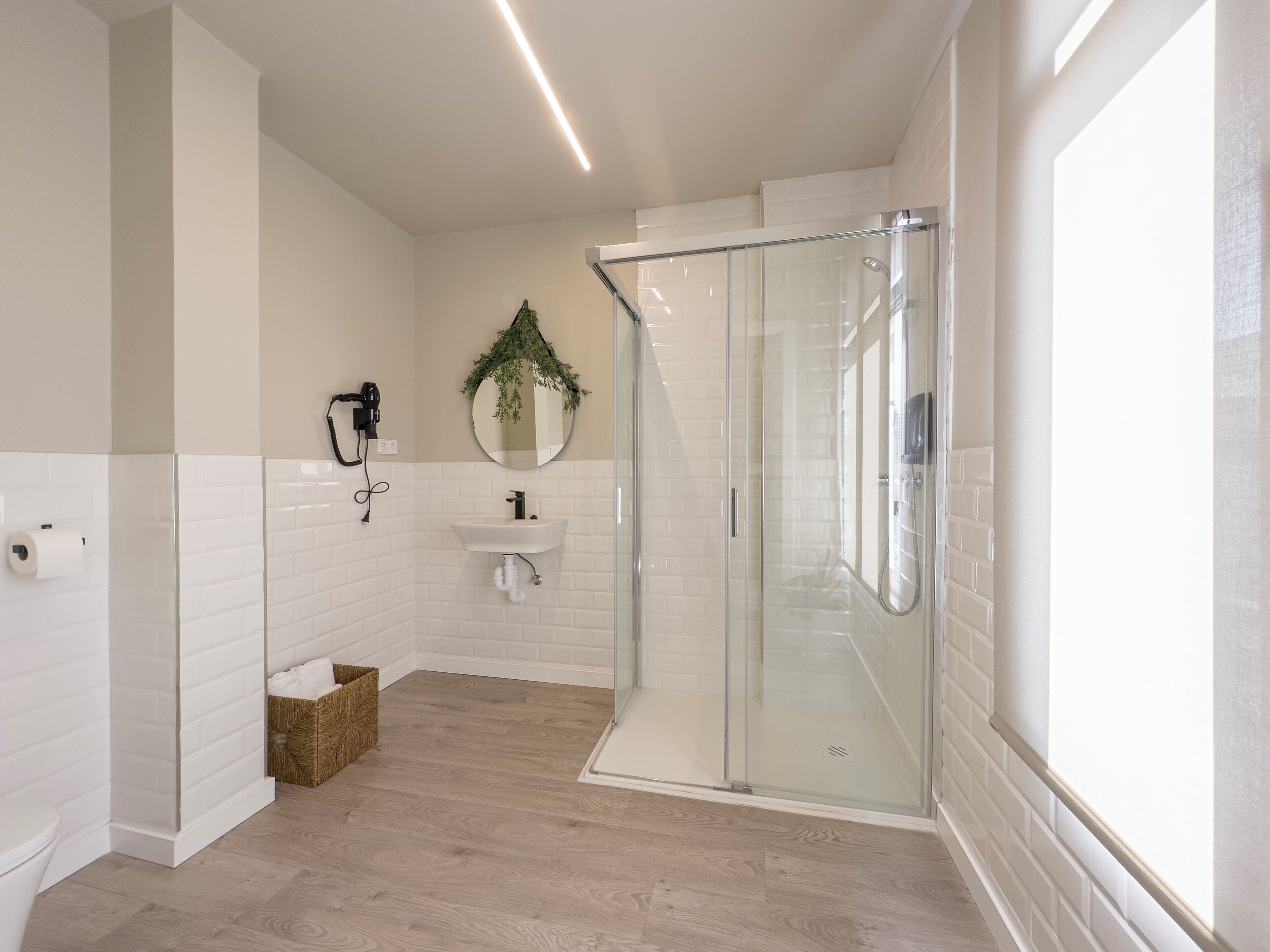 A modern bathroom with a glass shower enclosure, a white sink, and a toilet.