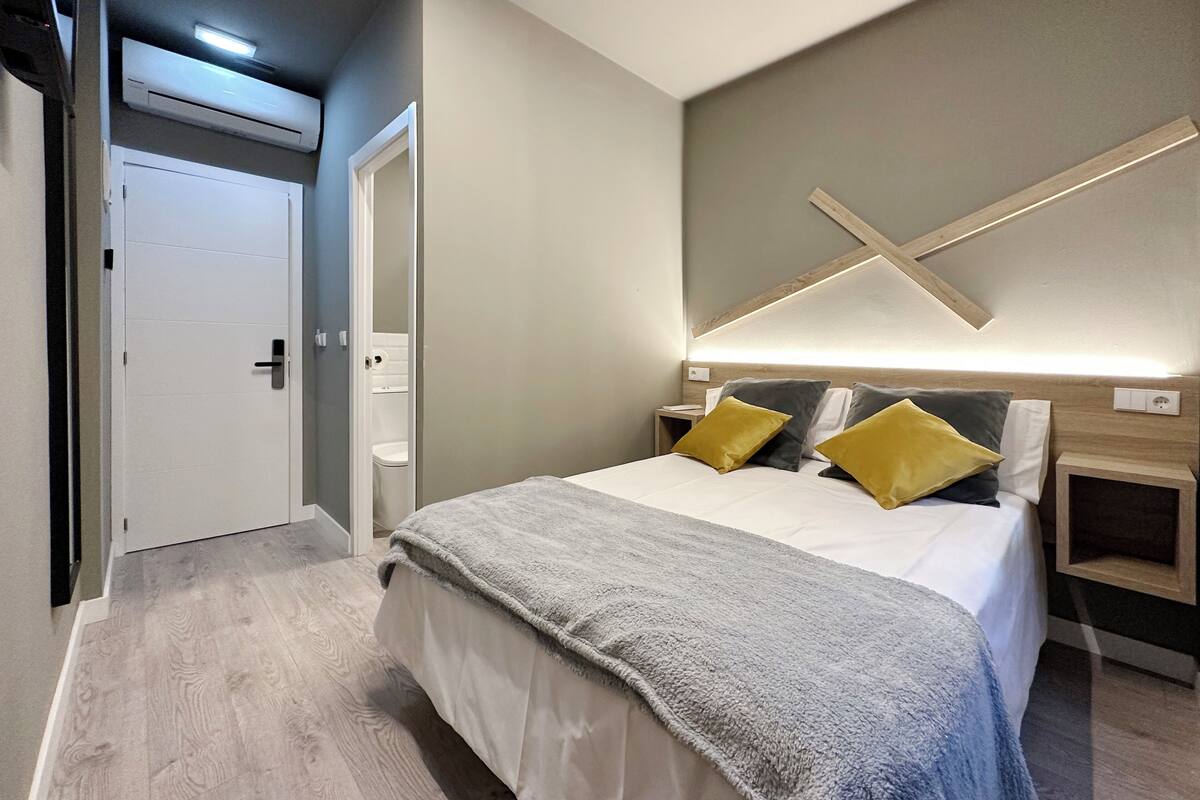A modern bedroom with a large bed, bedside tables, a wardrobe, and a ceiling light fixture.