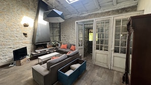 A cozy living room with a stone wall, a fireplace, a sofa, and a television.