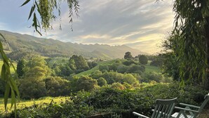 A wooden chair in a lush green landscape with a view of distant hills.