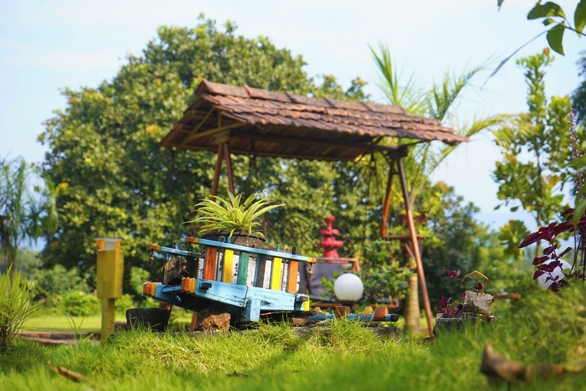 A model train set in a garden with a rustic shelter and a small plant.