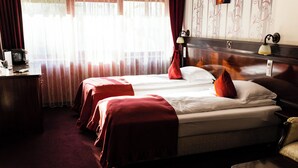 Une chambre d’hôtel avec deux lits, un bureau, une lampe et une vue sur l’extérieur.