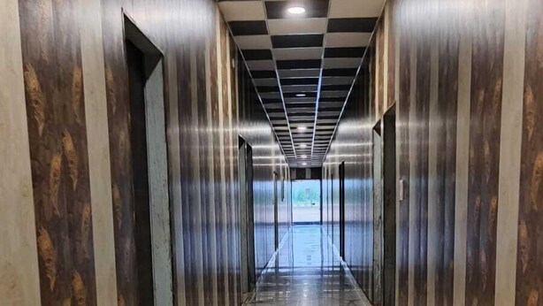 A corridor with marble flooring and patterned walls, leading to an open area with a view.