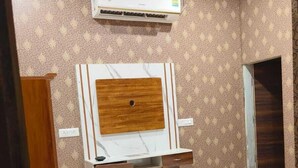 A bedroom with a bed, a built-in wardrobe, an air conditioning unit, and patterned wallpaper.