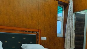 A bedroom with a wooden bed, a window with a view, and an air conditioning unit.
