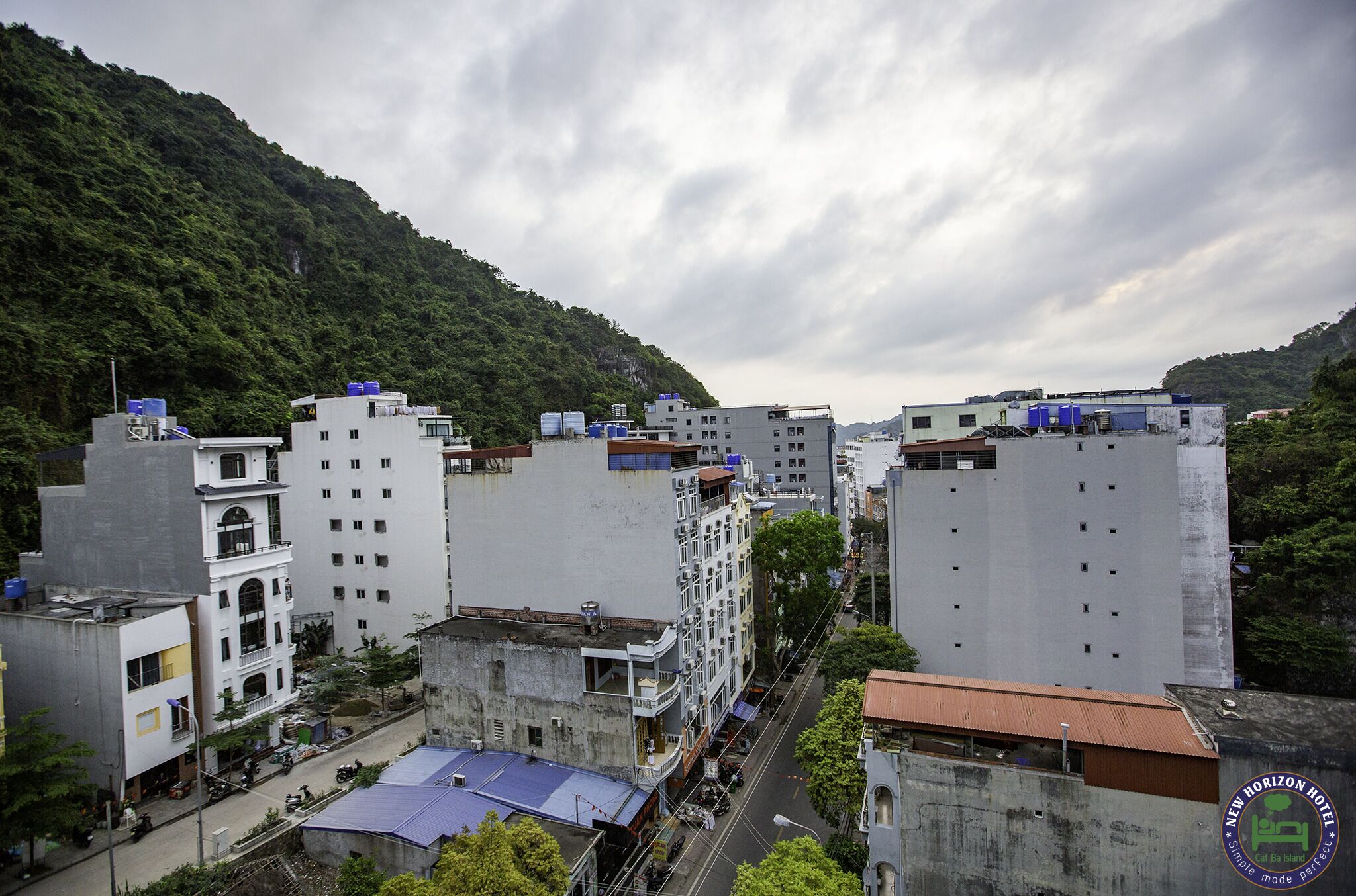 A multi-story hotel with a central courtyard, surrounded by buildings and a mountainous backdrop.