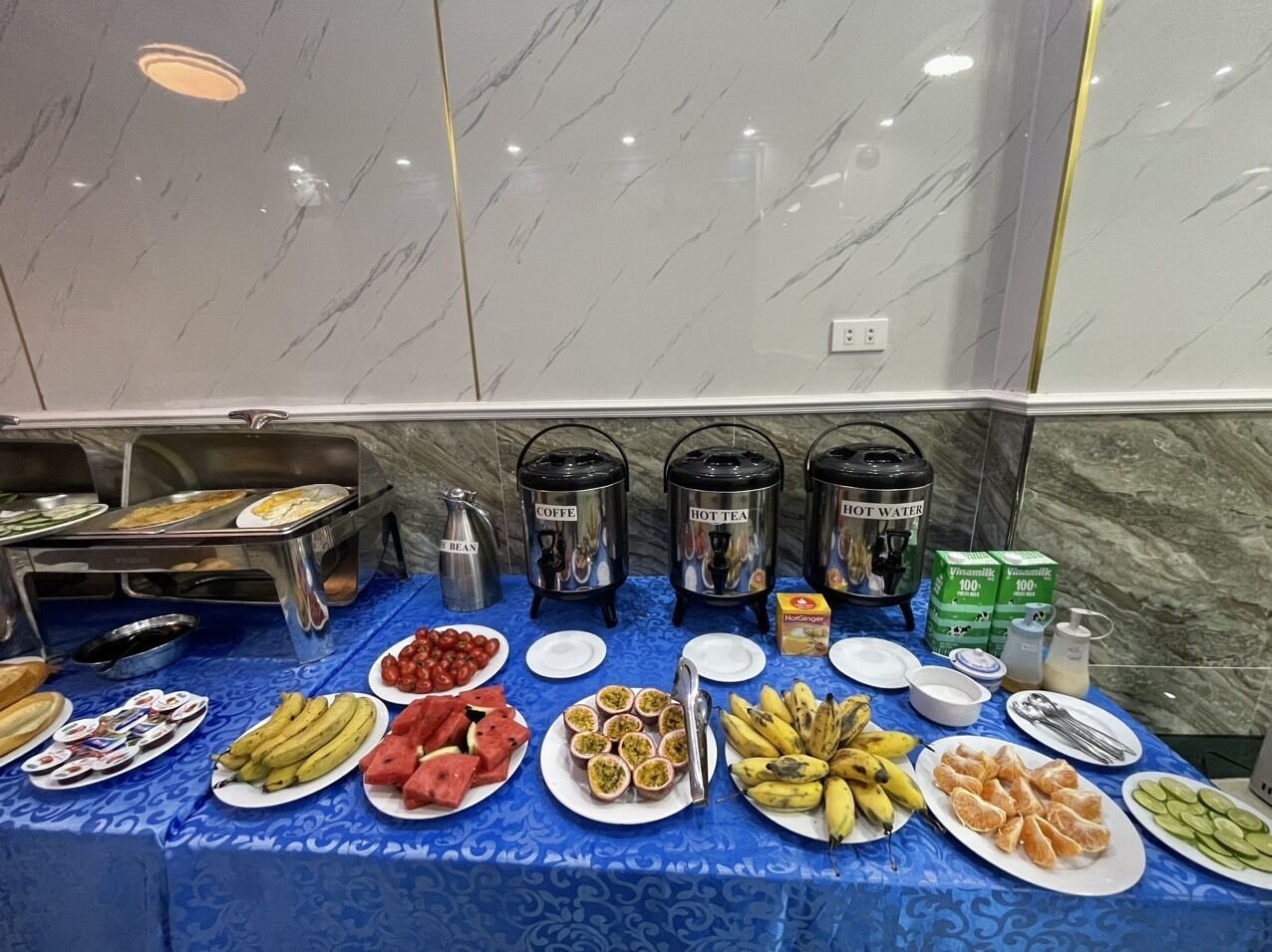 Uma mesa de buffet com diversos alimentos e máquinas de bebidas.