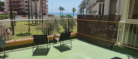 A balcony with two chairs, a view of the sea, and a wooden fence.