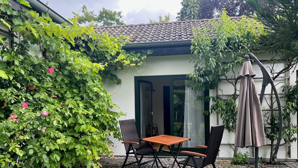 Un patio con tavolo e sedie, un ombrellone e un vialetto in mattoni.