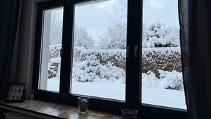 Una finestra con vista su un giardino innevato.