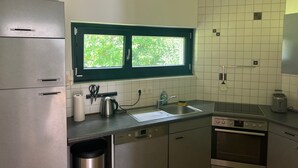 Una cucina moderna con elettrodomestici in acciaio inossidabile, una finestra vista su spazi verdi e pareti rivestite di piastrelle bianche.