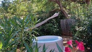 An outdoor hot tub surrounded by lush greenery and a wooden deck. - Bastide Cedrea (Peyrolles-en-Provence)