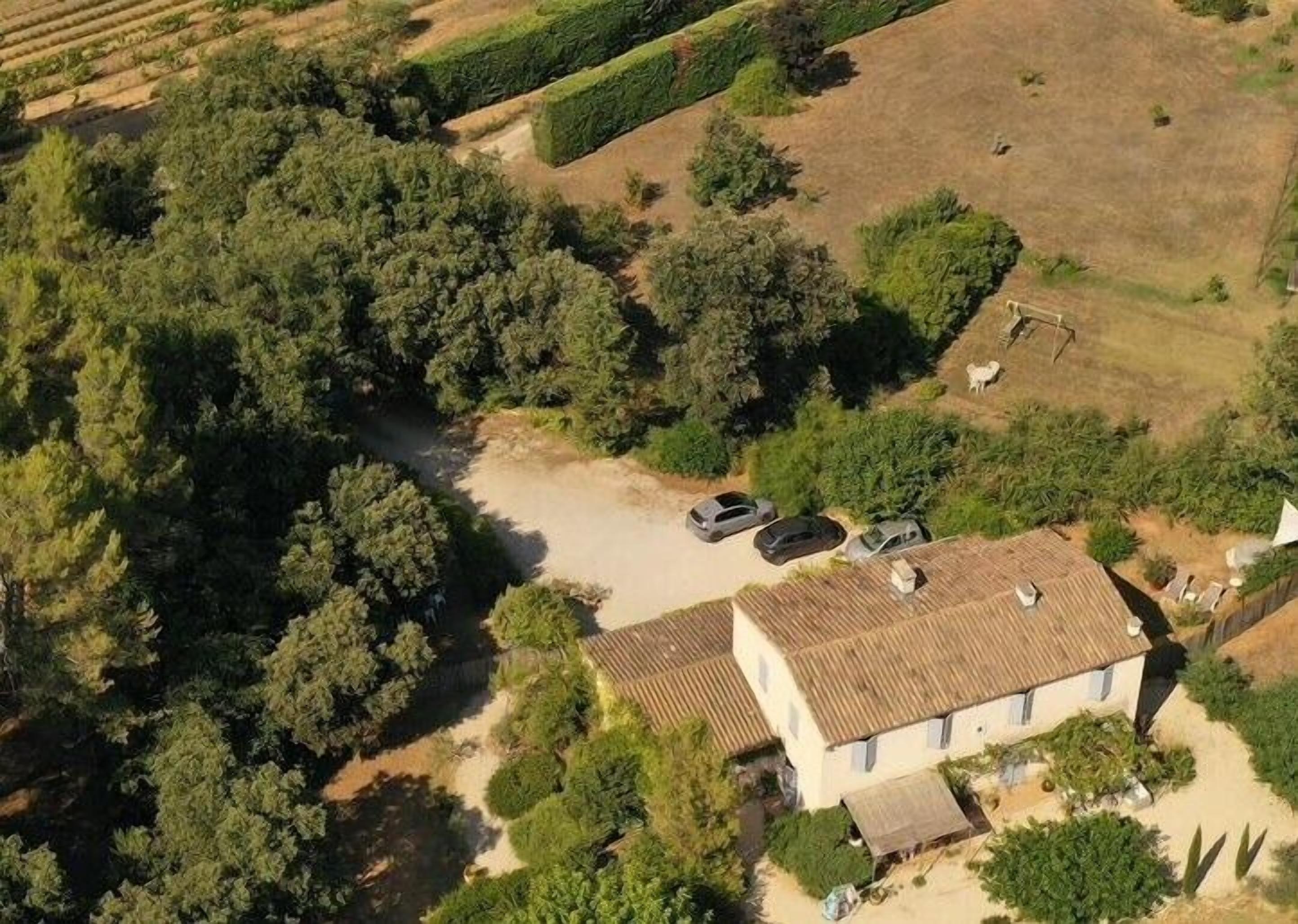 Vue aérienne d’une propriété comprenant une grande maison, une allée et des voitures garées.