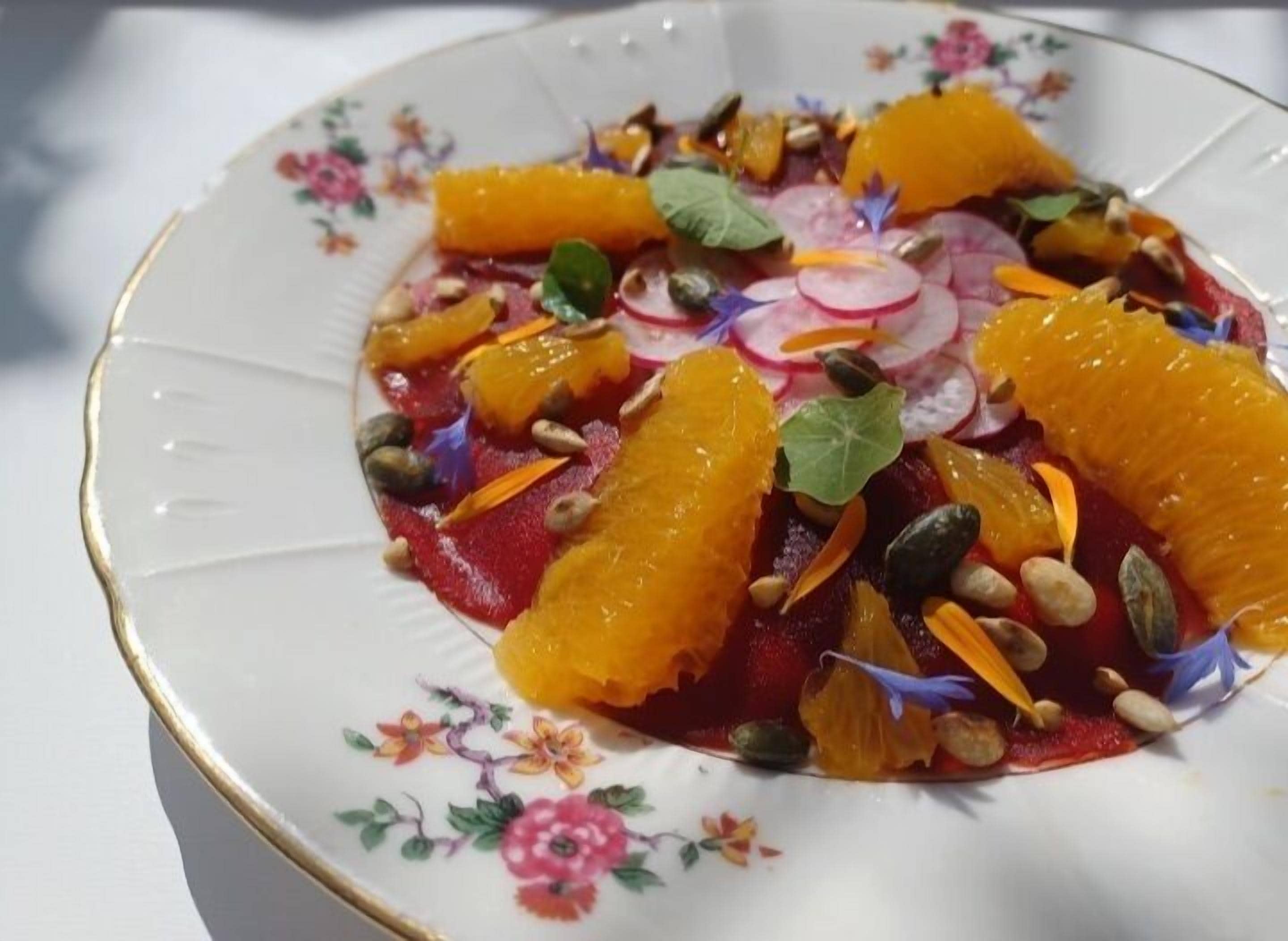 A plate of food with orange segments, radish slices, and seeds.