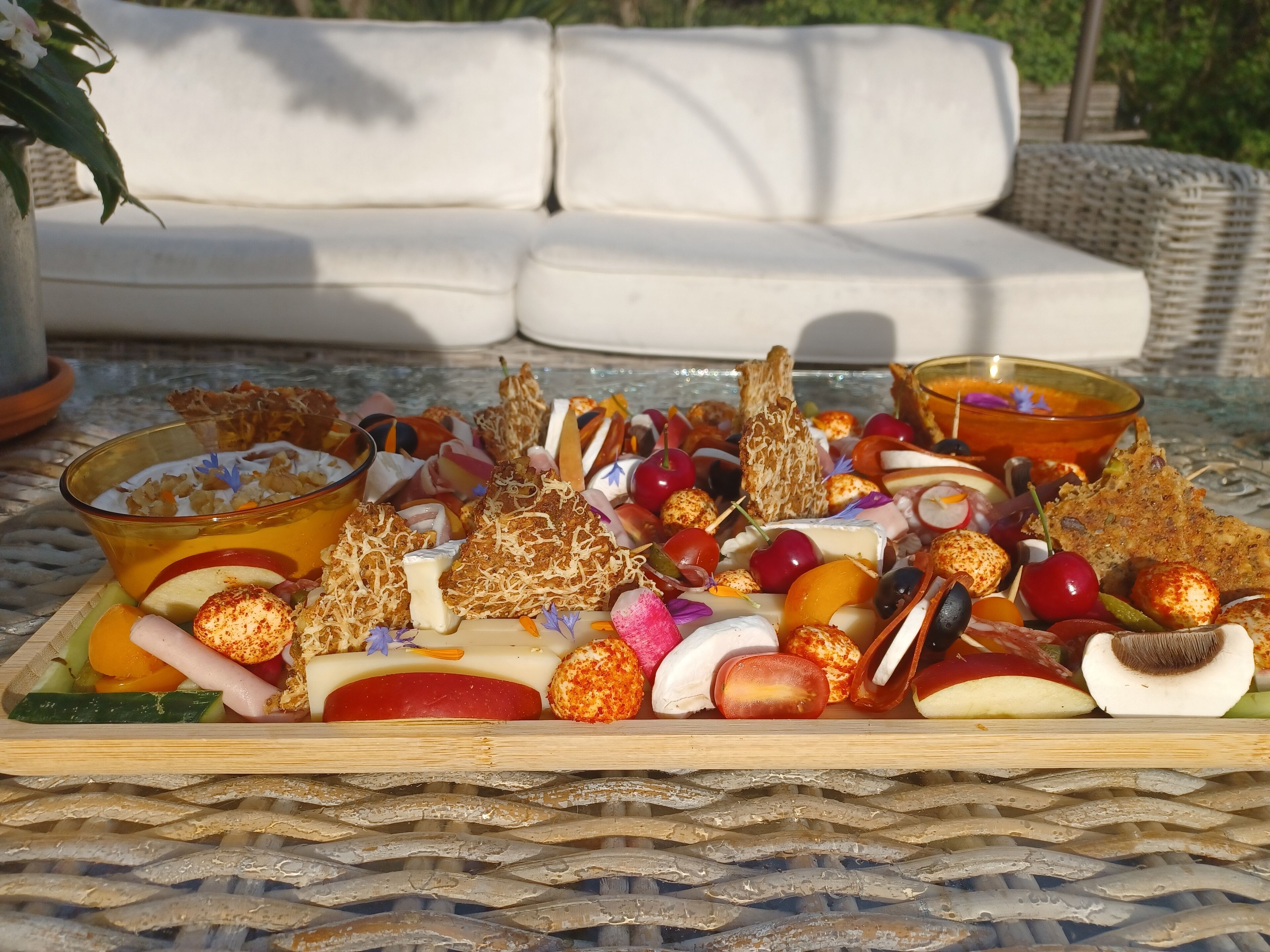 Une planche de charcuterie garnie de différents fromages, de fruits et de noix, le tout disposé sur une nappe tissée.