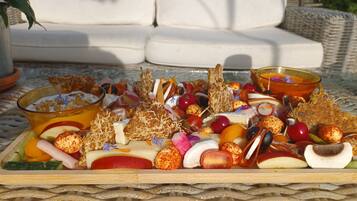 Une planche de charcuterie garnie de différents fromages, de fruits et de noix, le tout disposé sur une nappe tissée.