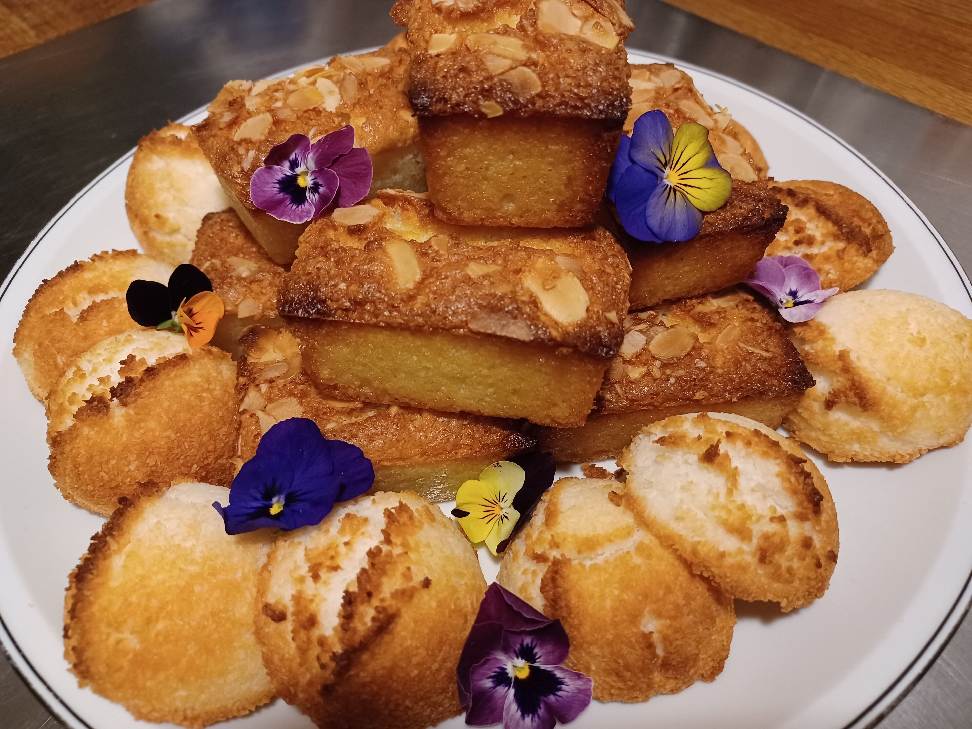 Une assiette de beignets frits, garnis d’amandes et de fleurs comestibles.