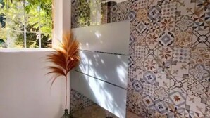 A bathroom with a large window, a shower with a geometric tile pattern, and a potted plant. - Bastide Cedrea (Peyrolles-en-Provence)