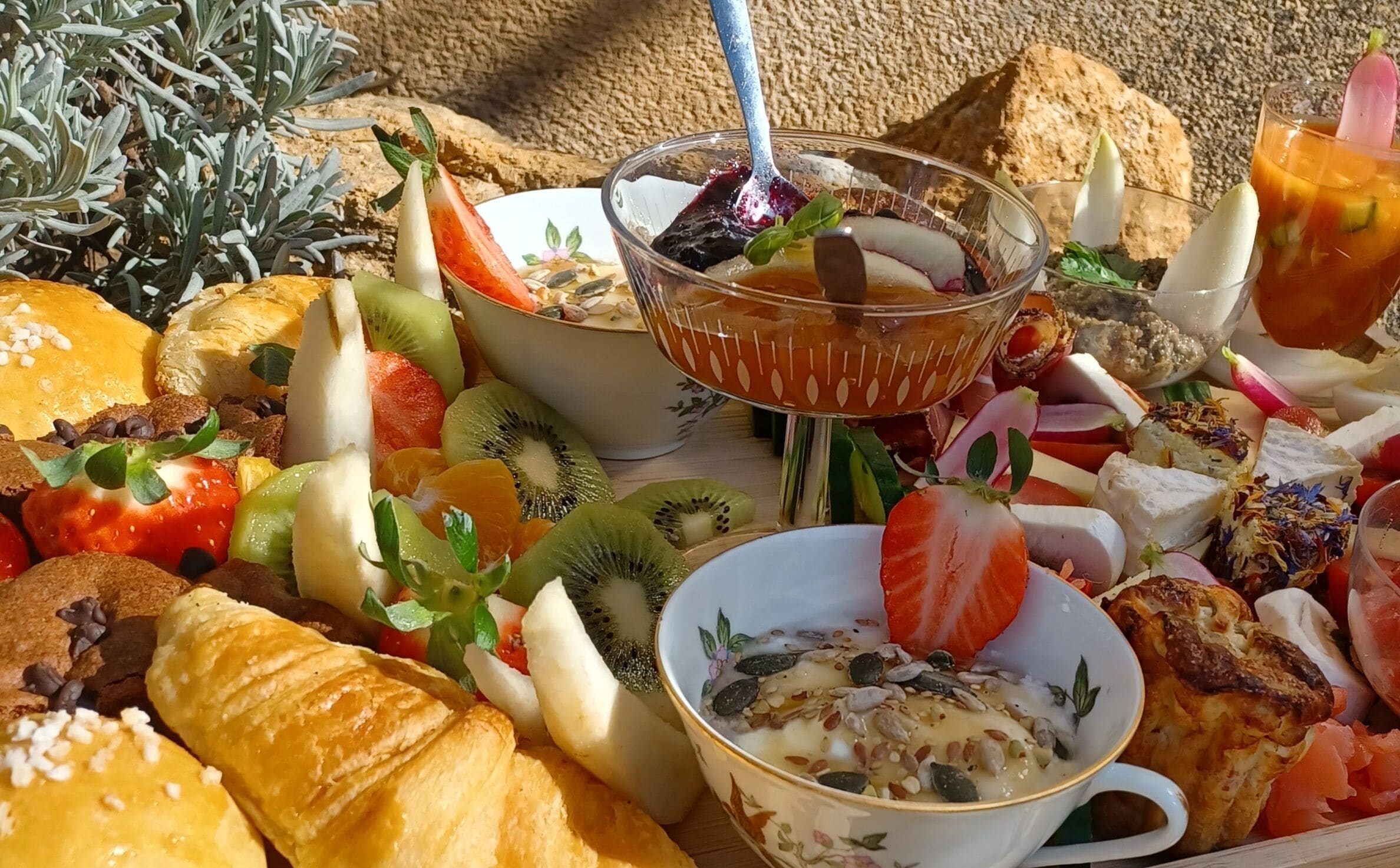 A breakfast spread with various fruits, pastries, and a bowl of cereal.
