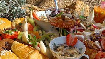 A breakfast spread with various fruits, pastries, and a bowl of cereal.