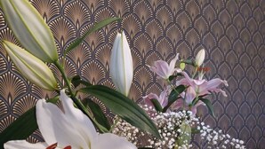 A table with a vase of flowers, including lilies and baby's breath, against a patterned wallpaper background. - Bastide Cedrea (Peyrolles-en-Provence)