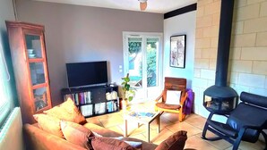A living room with a sofa, a television, a bookshelf, a chair, and a fireplace.