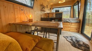 Un interior de cabaña acogedor con comedor, cocina y zona de descanso con vistas.
