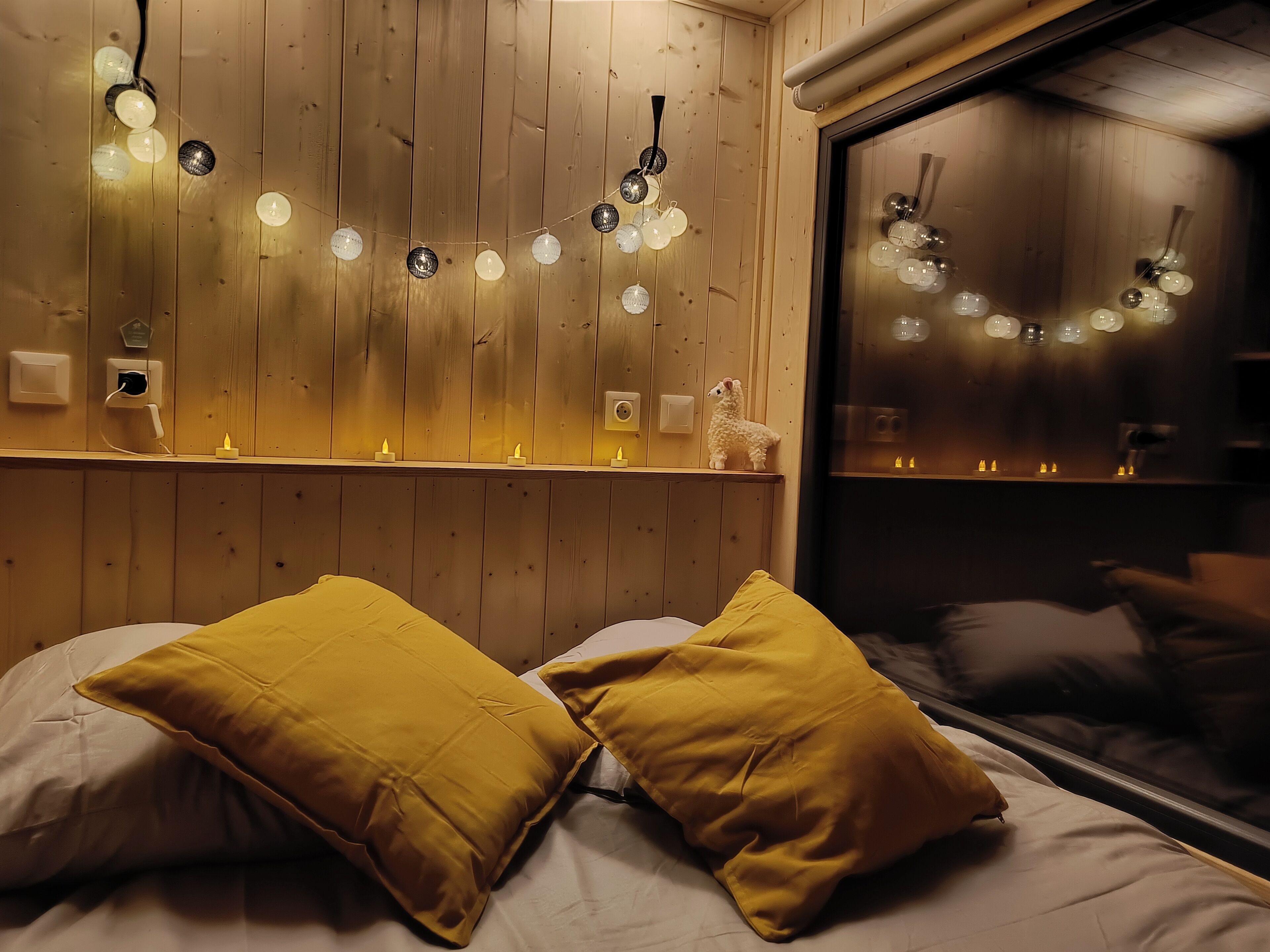 Una habitación con paredes de madera, una cama con almohadillas amarillas y luces de adorno en la pared.
